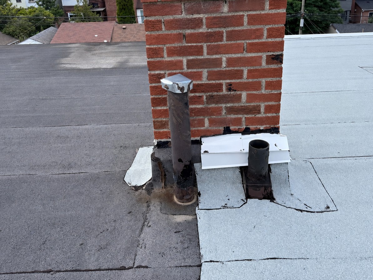 Before: worn metal flashing and cracked membrane around a chimney