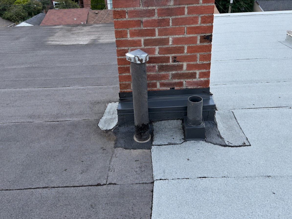 After: new metal flashing and membrane repair around a chimney on a flat roof